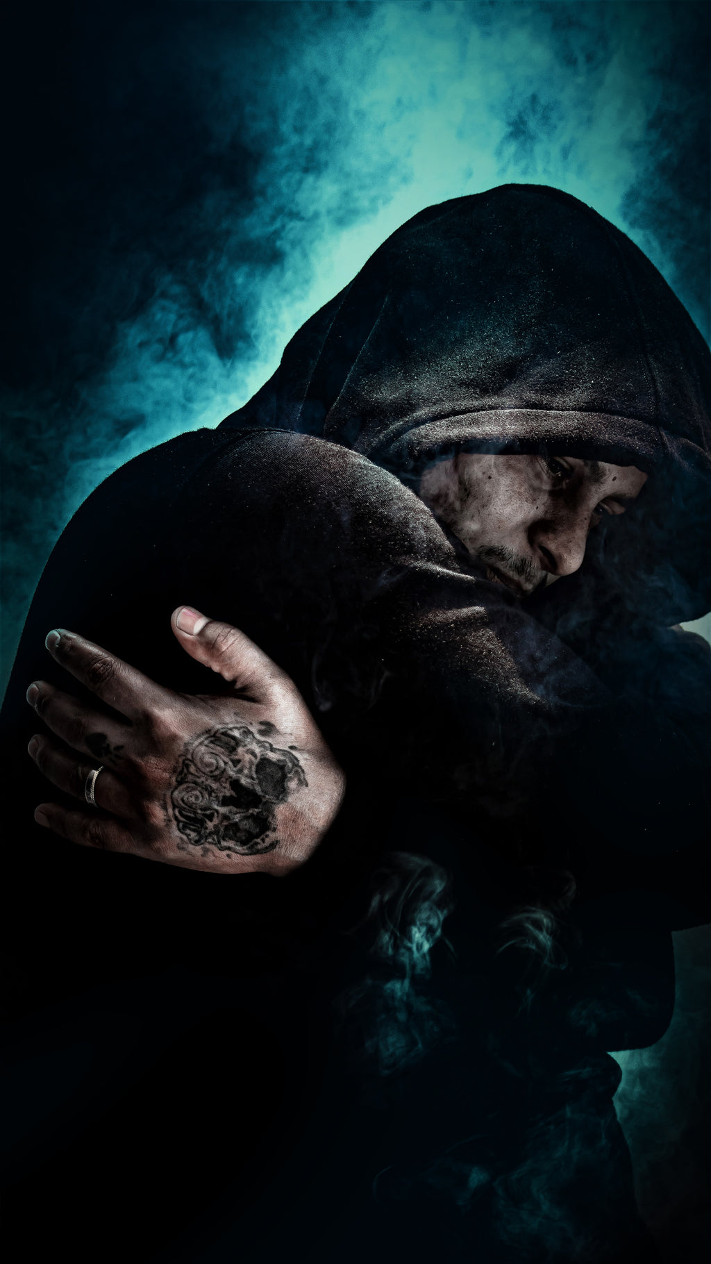 Dark cinematic fine art portrait of Marco, hooded and mysterious, emerging from shadow and teal smoke with a tattooed hand visible