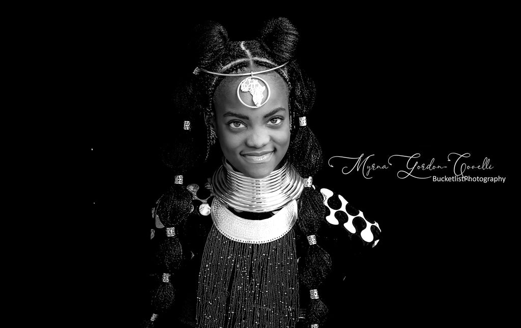 Black and white fine art portrait of Wandile wearing layered silver neck rings, ornate silver headpiece with Africa pendant and traditional beaded dress