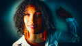 Fine art editorial portrait of Hope with natural curls, layered gold neck rings and orange beaded earrings in warm amber and teal tones