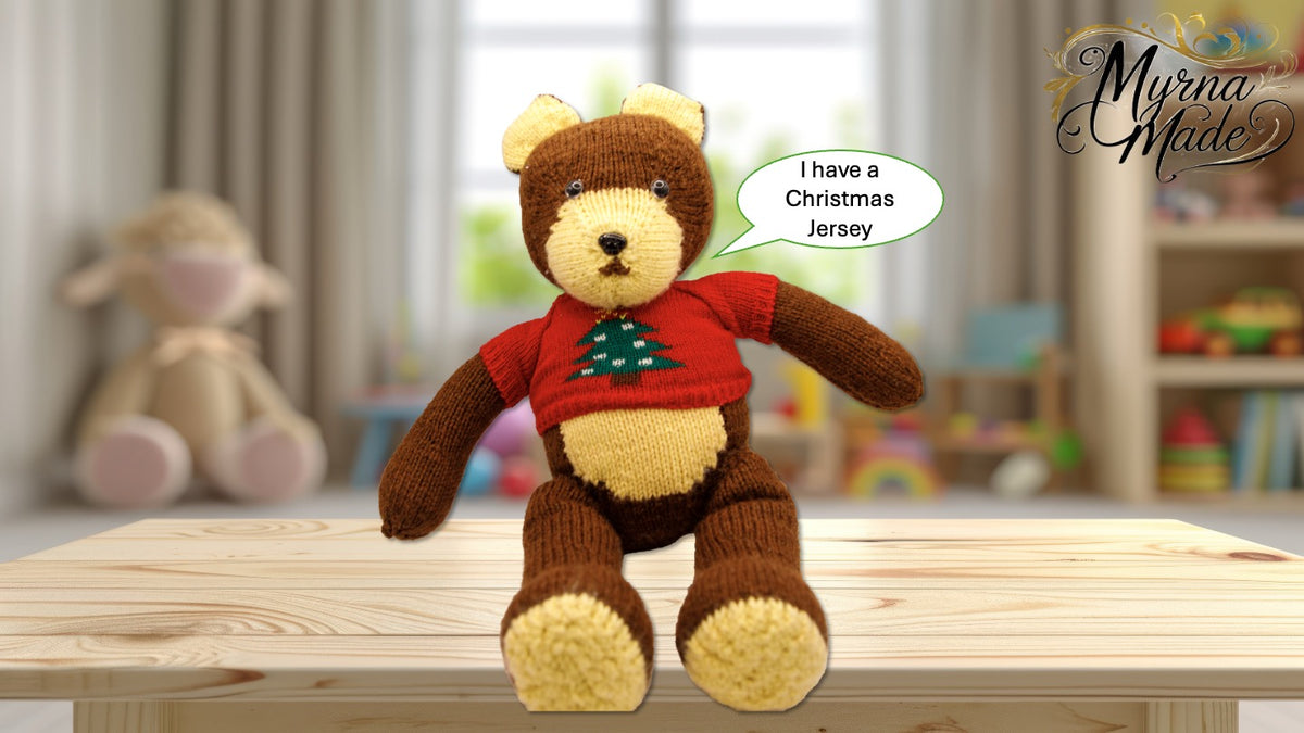 Teddy bear wearing a red sweater with a Christmas tree design, sitting on a wooden surface.