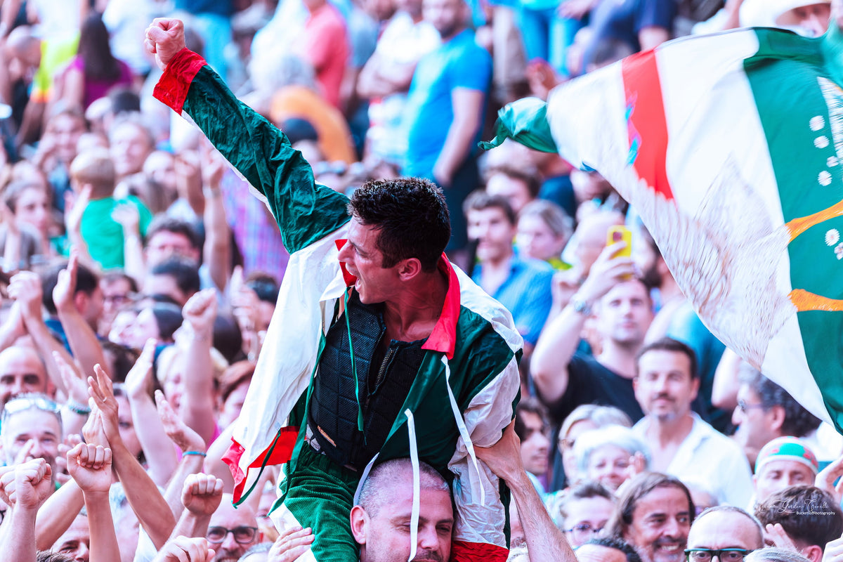 Goose contrada supporter lifted on shoulders, fist raised in triumph at the Palio di Siena victory celebration, 3 July 2025