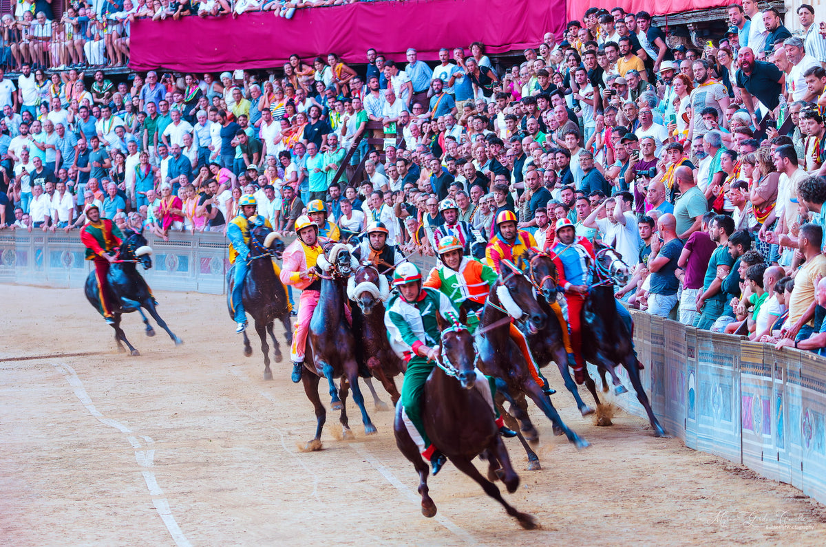 Jockeys in colourful contrada silks racing on horseback around the Campo at the Palio di Siena with packed grandstands, 3 July 2025