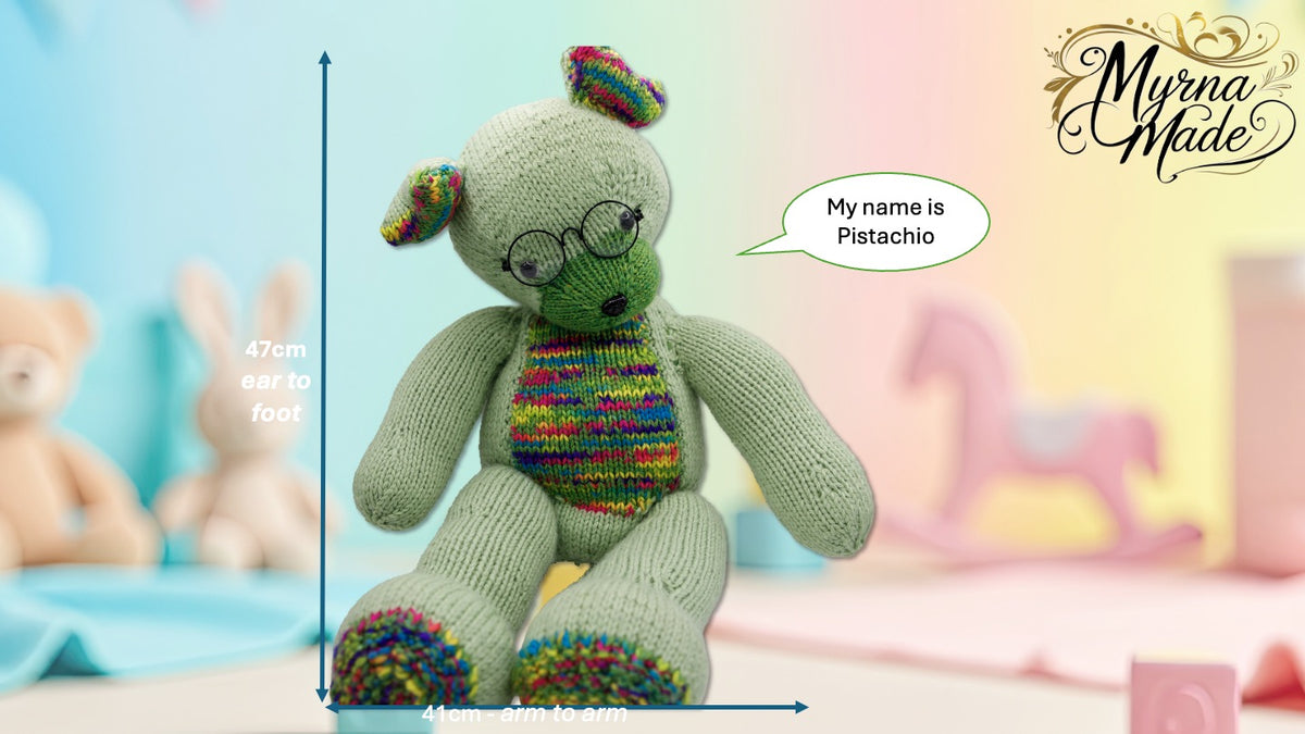 Knitted teddy bear with colorful pattern and glasses, standing on a light surface with a soft, blurred background.