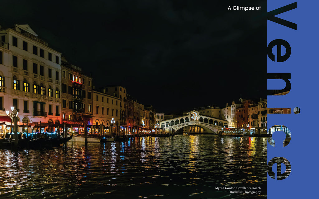 Rialto Bridge illuminated at night over the Grand Canal, Venice, with gondolas and lantern-lit waterfront